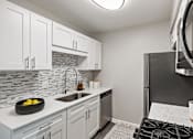Thumbnail 6 of 31 - A kitchen with a black stove top oven and a white counter top.