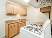 Thumbnail 12 of 31 - A white gas stove is in a kitchen with wooden cabinets.