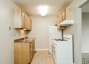 Thumbnail 11 of 31 - A kitchen with a white fridge and wooden cabinets.