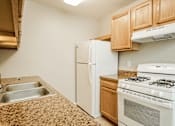 Thumbnail 13 of 31 - A kitchen with a white refrigerator, stove, and sink.