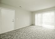 Thumbnail 15 of 31 - A room with a carpeted floor, a door, and a window with blinds.