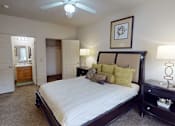 Thumbnail 14 of 35 - A bedroom with a large bed and a ceiling fan.