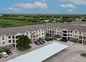 Thumbnail 32 of 35 - Apartment complex with a parking lot in front.