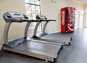 Thumbnail 23 of 35 - A Coca-Cola vending machine is in a room with treadmills.
