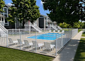 Thumbnail 1 of 10 - A pool surrounded by a metal fence with chairs on it.