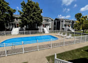 Thumbnail 2 of 10 - A pool surrounded by a fence with a building in the background.