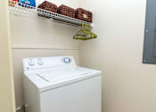 Thumbnail 10 of 33 - A white washing machine sits in a laundry room.