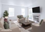 Thumbnail 3 of 33 - A living room with a couch, chairs, a coffee table, and a fireplace.