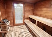 Thumbnail 17 of 33 - A wooden sauna with benches and a door.