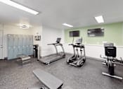 Thumbnail 19 of 39 - A gym with treadmills, elliptical machines, and a bench.