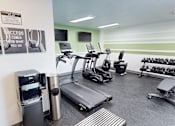 Thumbnail 18 of 39 - A gym with equipment, weights, and televisions.