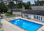Thumbnail 27 of 39 - A swimming pool surrounded by lounge chairs and a building in the background.
