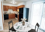 Thumbnail 2 of 29 - A kitchen with a table set for two and a vase of flowers on the table.