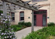 Thumbnail 2 of 22 - a historic brick building with a red door and a wooden pergola