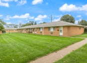 Thumbnail 18 of 25 - a brick building with a grass yard and a sidewalk