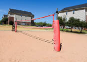 Thumbnail 23 of 30 - a red net on a sandy playground with houses in the background