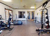 Thumbnail 17 of 32 - A gym with exercise equipment and a fan.