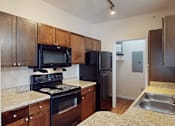 Thumbnail 8 of 32 - A kitchen with black appliances and wooden cabinets.