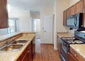 Thumbnail 4 of 32 - A kitchen with wooden cabinets and a black stove top oven.