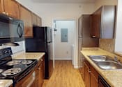 Thumbnail 5 of 32 - A kitchen with black appliances and wooden cabinets.