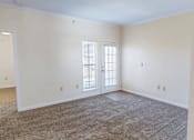 Thumbnail 12 of 32 - A room with a carpeted floor and a door with a window.