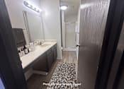 Thumbnail 6 of 20 - A bathroom with a sink, mirror, and rug.