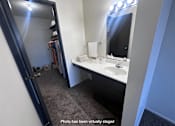 Thumbnail 7 of 20 - A bathroom with a sink, mirror, and a large mirror with lights above it.