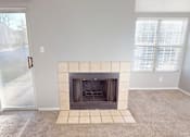 Thumbnail 15 of 30 - A living room with a fireplace and a sliding glass door.