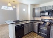Thumbnail 4 of 30 - A kitchen with a black stove top oven and microwave.