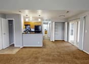 Thumbnail 10 of 30 - A spacious living room with a kitchen area in the background.