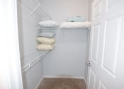 Thumbnail 11 of 39 - a walk in closet with white shelves and pillows