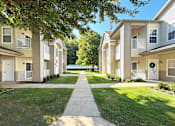 Thumbnail 35 of 37 - A sunny day at a residential complex with a pathway leading to the front door.