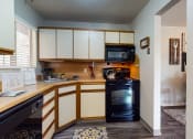 Thumbnail 3 of 10 - a kitchen with white cabinets and black appliances