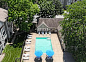 Thumbnail 17 of 29 - A pool surrounded by chairs and trees.