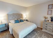 Thumbnail 10 of 29 - A bedroom with a large bed and a nightstand with a lamp.