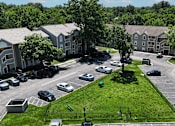 Thumbnail 26 of 29 - A dog park near a parking lot with cars and apartment buildings in the background.