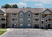 Thumbnail 24 of 29 - A large apartment complex with a parking lot in front.
