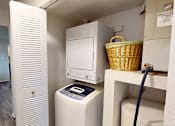 Thumbnail 8 of 29 - A white washing machine and dryer in a small laundry room.