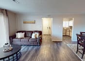 Thumbnail 4 of 29 - A living room with a brown couch and a coffee table.