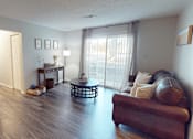 Thumbnail 2 of 29 - A living room with a brown leather couch and a glass coffee table.