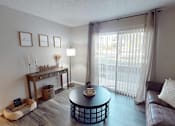 Thumbnail 3 of 29 - A living room with a brown leather couch, a round coffee table, and a dog bed.