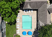 Thumbnail 19 of 29 - An aerial view of a swimming pool surrounded by trees and buildings.