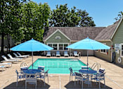 Thumbnail 16 of 29 - A pool surrounded by chairs and umbrellas with a house in the background.