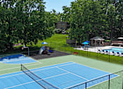 Thumbnail 26 of 36 - A blue tennis court surrounded by a black fence.