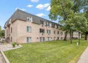 Thumbnail 20 of 20 - a large brick building with a grassy area in front of it