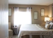Thumbnail 10 of 31 - a bedroom with a bed and a chair in front of a window