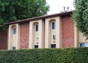 Thumbnail 29 of 31 - a brick building with arched windows and a hedge in front of it