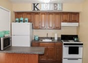 Thumbnail 4 of 31 - apartment kitchen with wood cabinets and white appliances