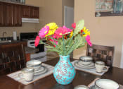 Thumbnail 5 of 31 - a vase of flowers on a table with plates and cups