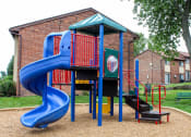 Thumbnail 20 of 31 - a playground with a blue slide in front of a brick building